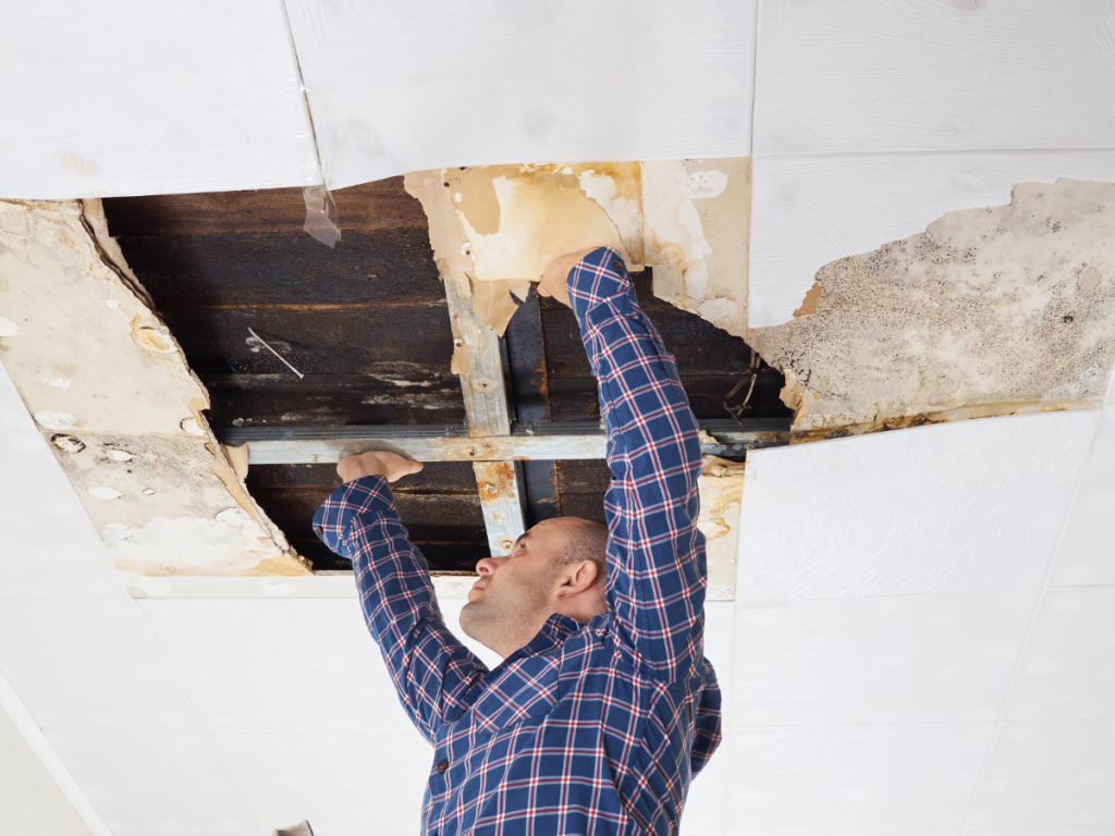 A man patching a hole in a ceiling