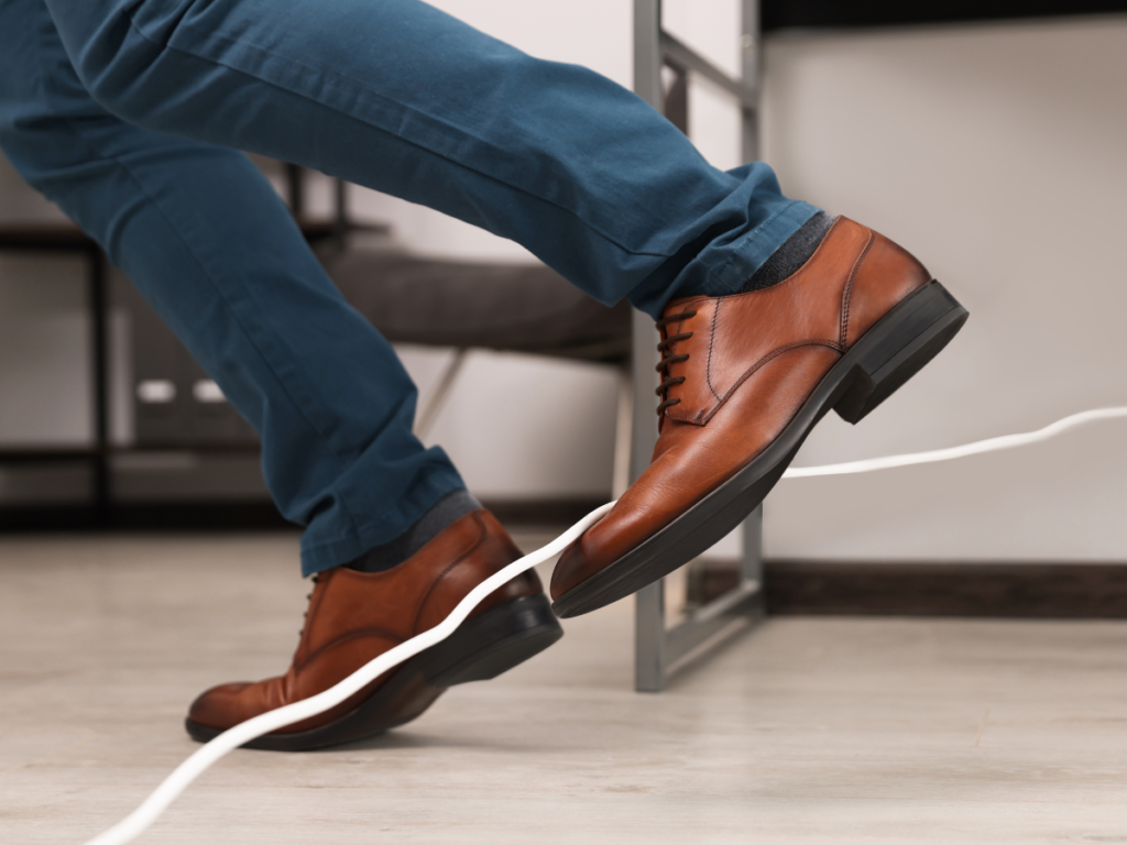 A well dressed man slipping over a white extension cord on the ground.